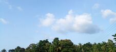 An Evening Sunset Scene With Clear Blue Clouds In A Rural Setting. A Beautiful Scene With Coconut Trees And Other Plants In The Ba Royalty Free Stock Photography