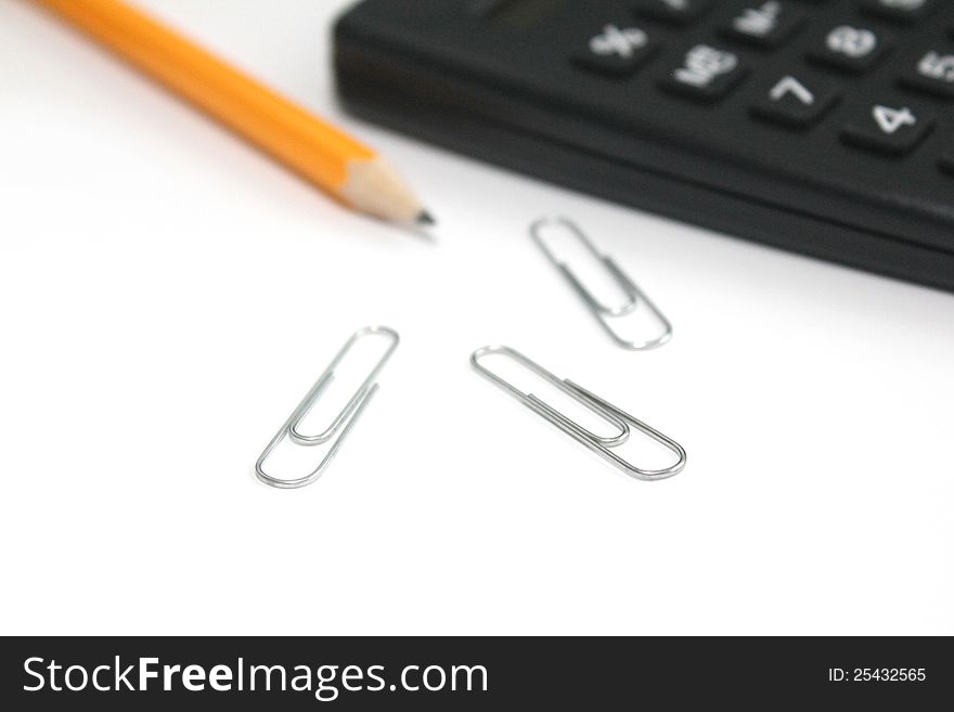 Calculator, pencil and paper clips over white piece of paper. Calculator, pencil and paper clips over white piece of paper