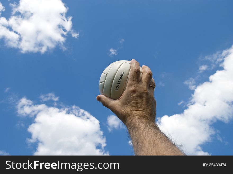 Small volley ball in man's hand against blue sky. Small volley ball in man's hand against blue sky