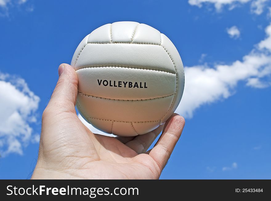 Volley ball in man's hand on blue sky