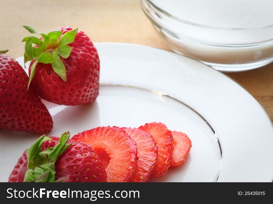 Whole and sliced ripe strawberries on a white plate. Whole and sliced ripe strawberries on a white plate