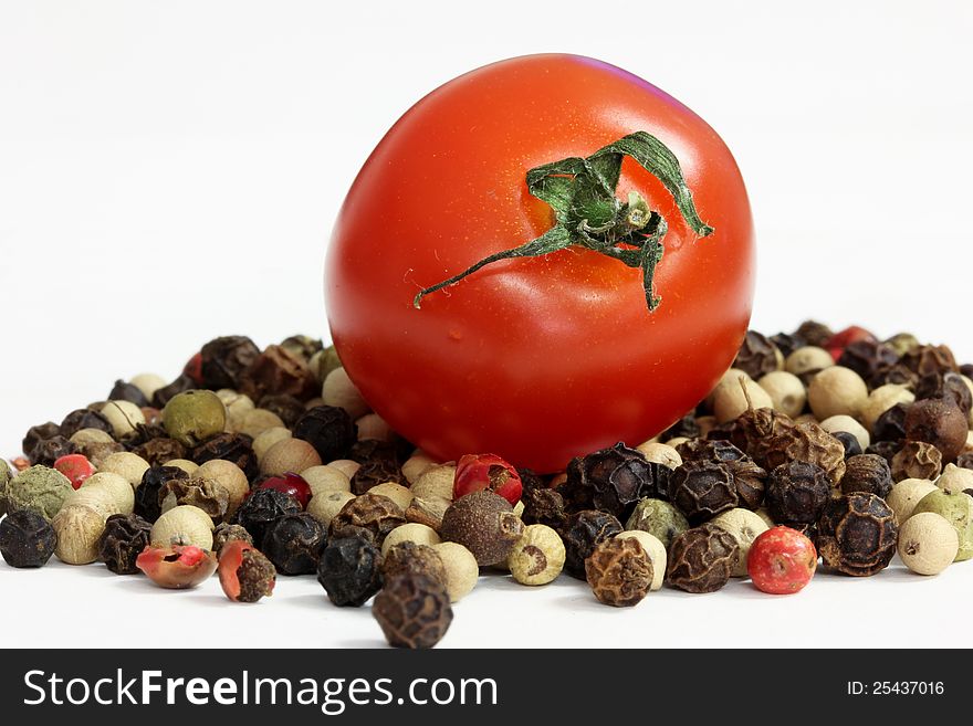 A cherry tomato lying on some peppercorns. A peppered tomato. A cherry tomato lying on some peppercorns. A peppered tomato