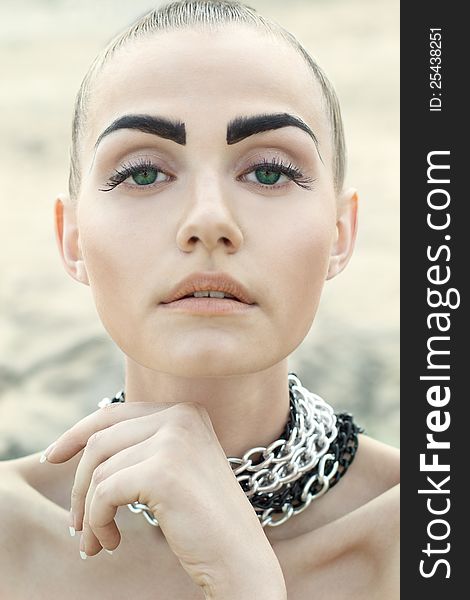 Fashion portrait of beautiful woman with chained neck posing on lightfull background