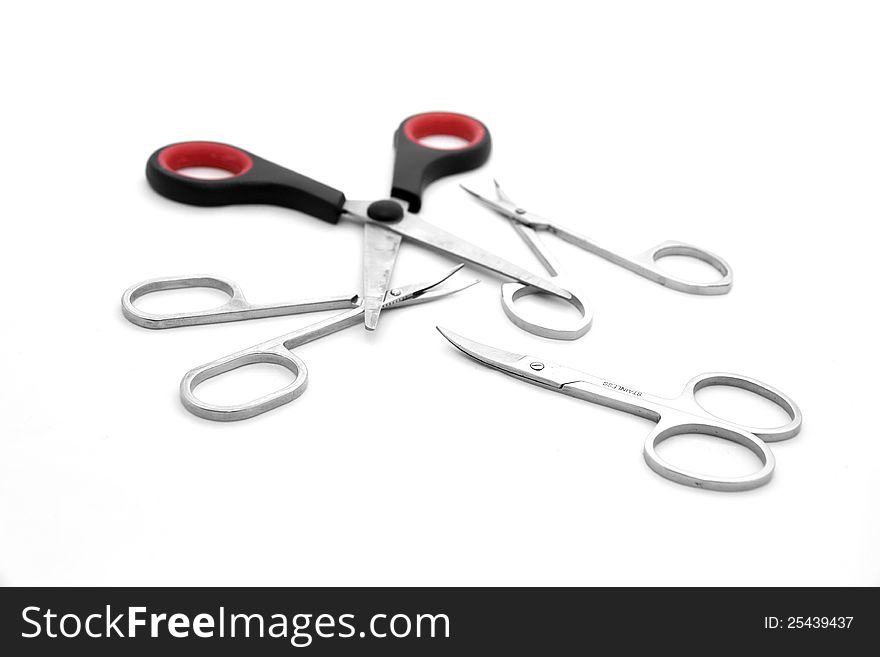 Four scissors on a white background, three metal nail clippers and a pair of red plastic handle. Four scissors on a white background, three metal nail clippers and a pair of red plastic handle