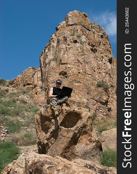 The man with the laptop sits in beautiful mountain district