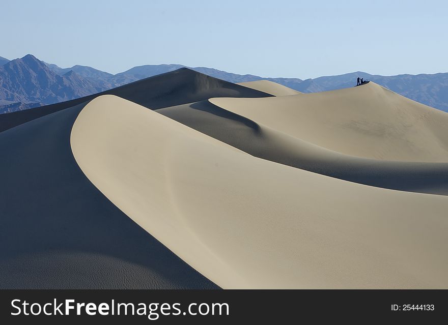 Two distant photographers atop the dunes in Death Valley National Park in early morning. Two distant photographers atop the dunes in Death Valley National Park in early morning.