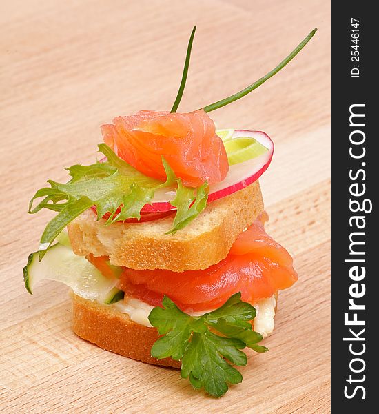 Appetizer of Smoked Salmon with Radish, Cucumber and Greens isolated on wooden background