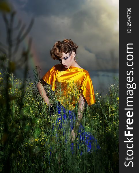 Beautiful young dreamy woman relaxing in the grass meadow. Dramatic sky. Beautiful young dreamy woman relaxing in the grass meadow. Dramatic sky