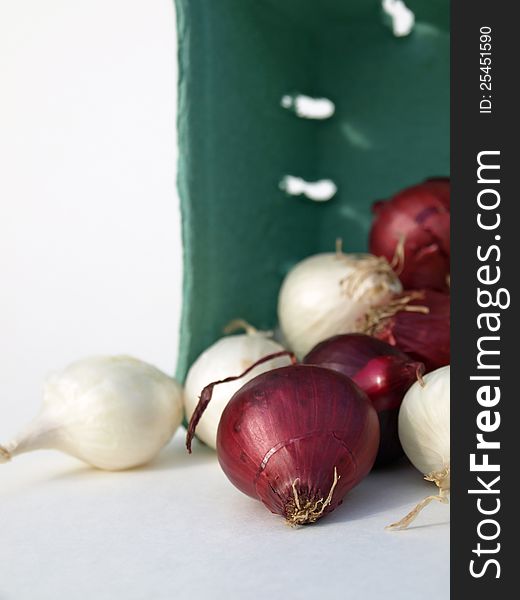 Red and white onions spilling out of container