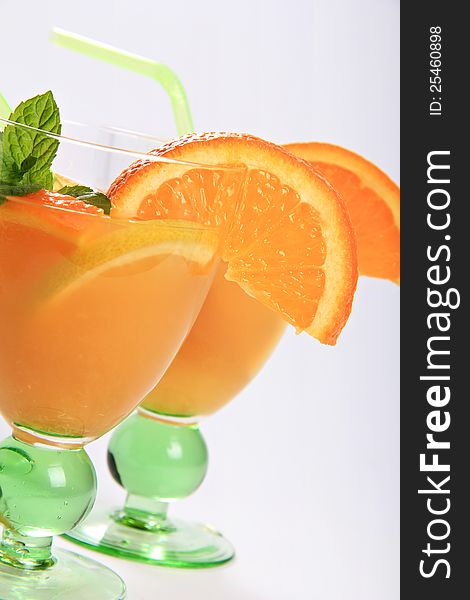 Detail of fruit cocktails with orange juice . Orange slice and mint leaves as decoration