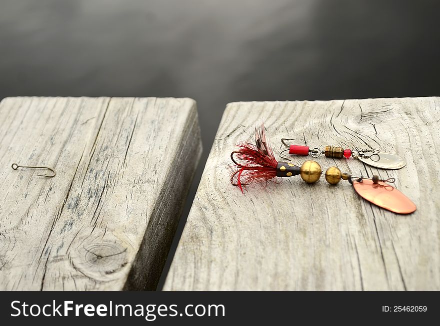 Fishing bait,wobbler on a bridge by the lake. And a hook on the side.