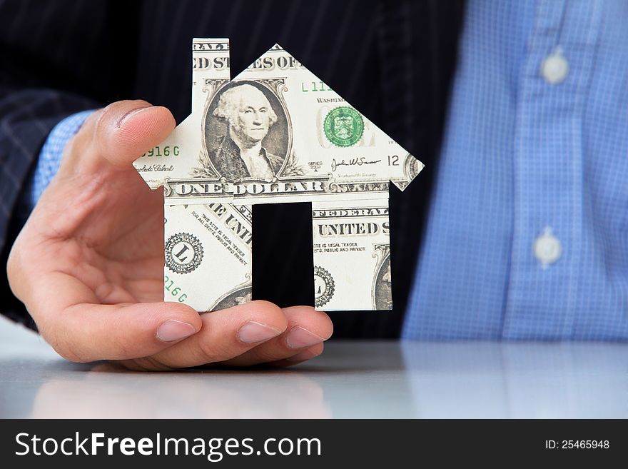 Business man holding banknote house icon
