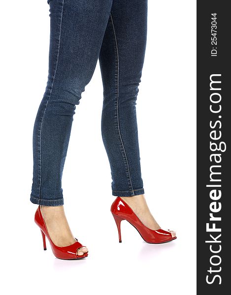 Pretty female legs in red high heel shoes and jeans isolated on white background. Pretty female legs in red high heel shoes and jeans isolated on white background