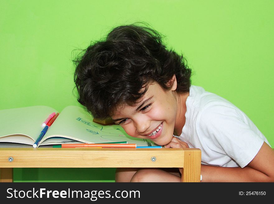 Little boy with curly hair enjoying his drawing at home. Little boy with curly hair enjoying his drawing at home