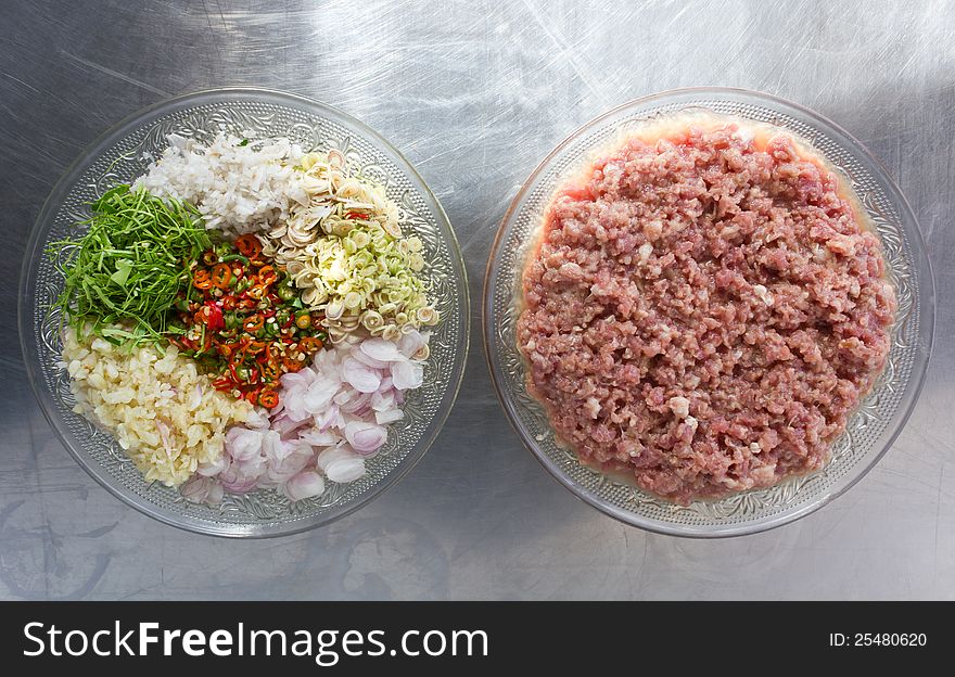 Sliced ​​pork with herbs in a glass dish placed on a stainless steel. Sliced ​​pork with herbs in a glass dish placed on a stainless steel.