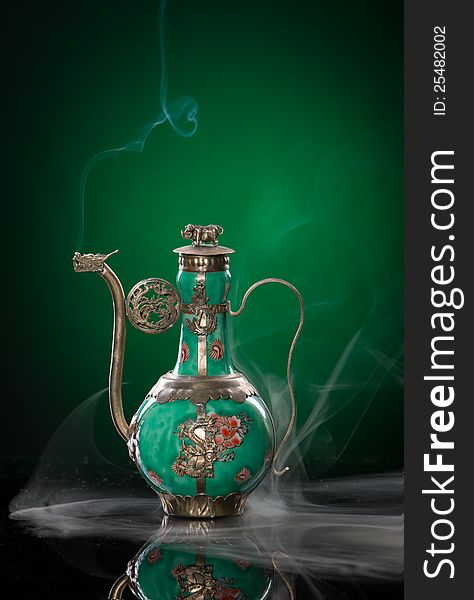 Dragon teapot with smoke against green backgroun