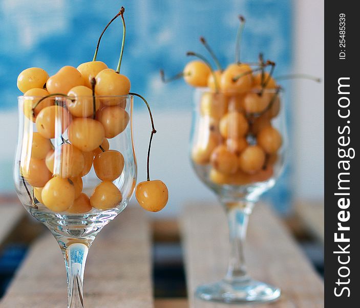 Two cups of white cherries on a blue background. Remind me for summer.