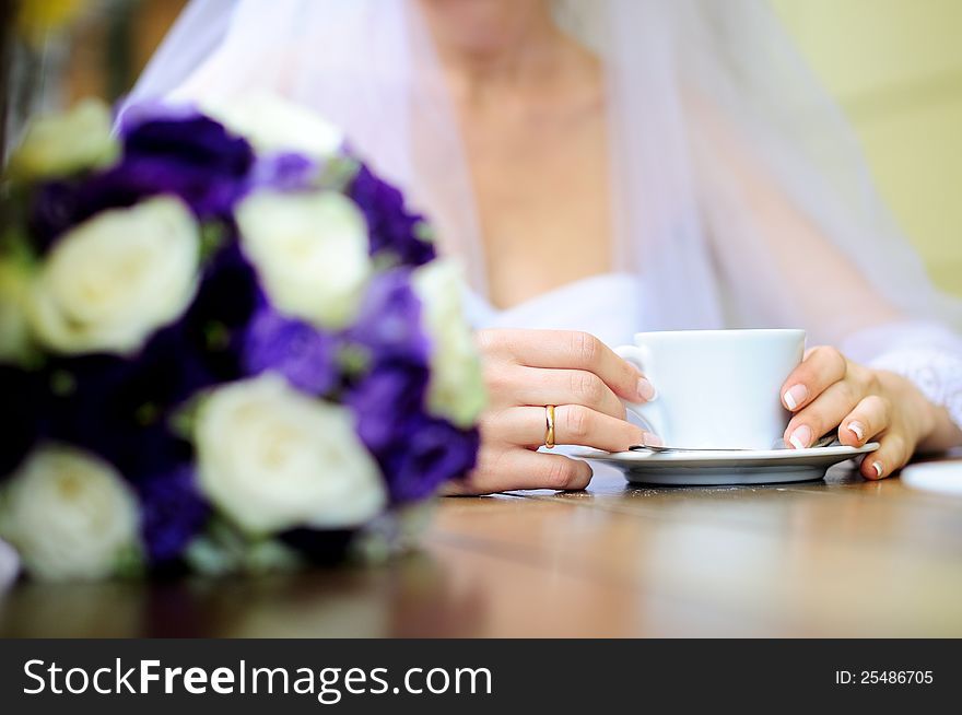 Bride holding coffee cup. Blur bride on a background.