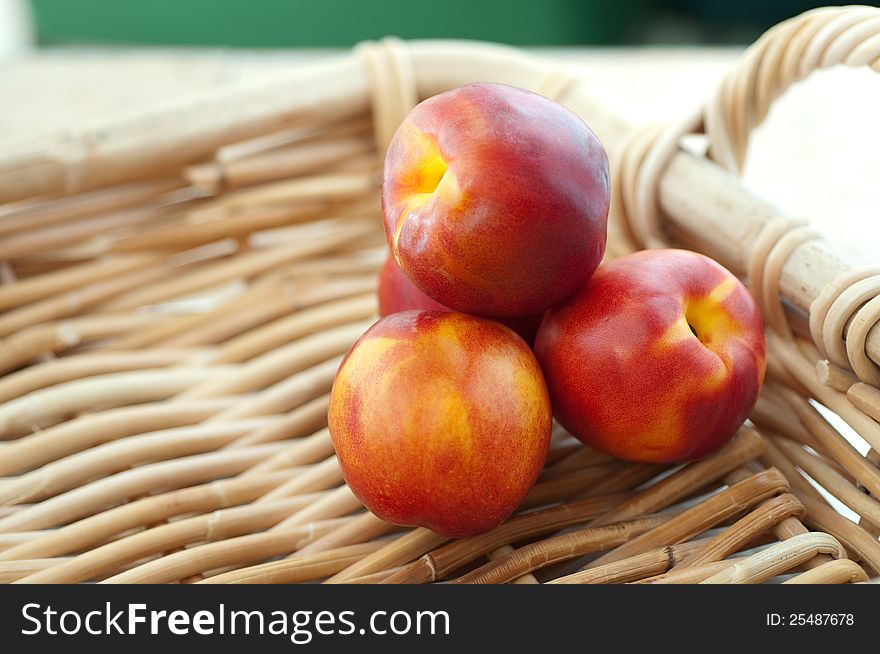 Four nectarines resting on woven reed basket. Four nectarines resting on woven reed basket