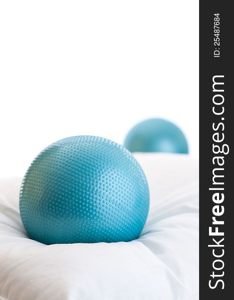 One blue exercise ball resting on pillow with a second ball in background, with plenty of white copy space. One blue exercise ball resting on pillow with a second ball in background, with plenty of white copy space