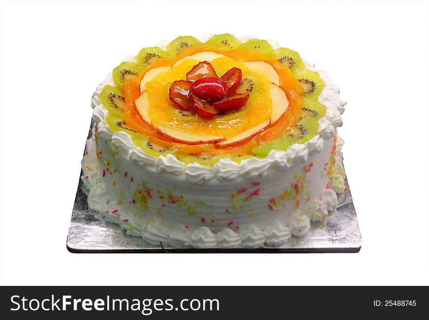 Delicious and yummy white birthday and party cake with sliced fruit pieces of kiwi, orange, plums and apple decorated on the pastry surface isolated on white background with clipping path. Delicious and yummy white birthday and party cake with sliced fruit pieces of kiwi, orange, plums and apple decorated on the pastry surface isolated on white background with clipping path