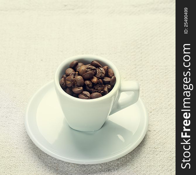 Coffee beans in a cup on white fabric