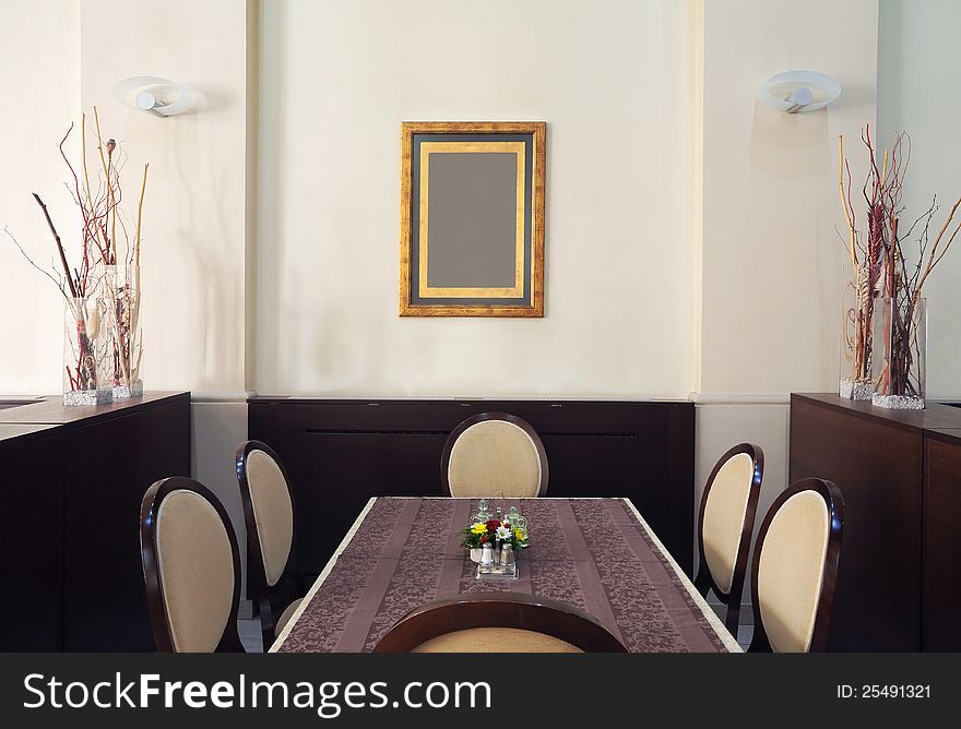 Just one corner of a restaurant, empty table and chairs with empty frame on the wall. Just one corner of a restaurant, empty table and chairs with empty frame on the wall.