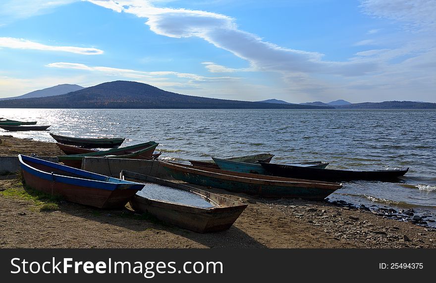 Boats on the shore against the backdrop of the lake and mountains. Russia, the National Park Zyuratkl