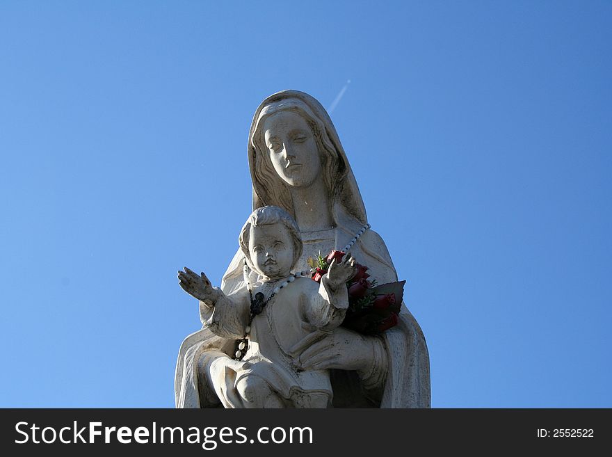 A statue of madonna and the child on a blue sky. A statue of madonna and the child on a blue sky