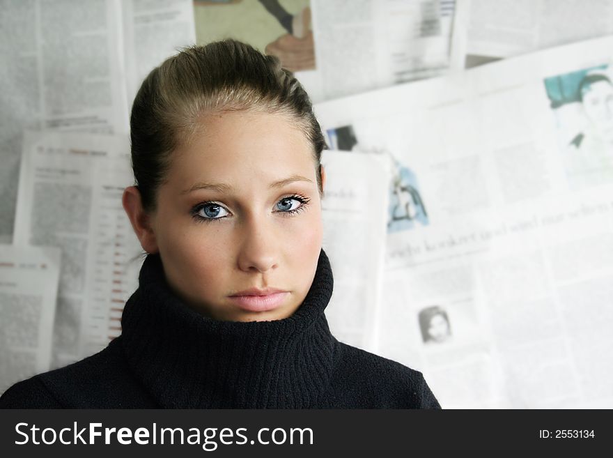 A beauty portrait of young businesswoman against a wall with a lot of newspapers. A beauty portrait of young businesswoman against a wall with a lot of newspapers