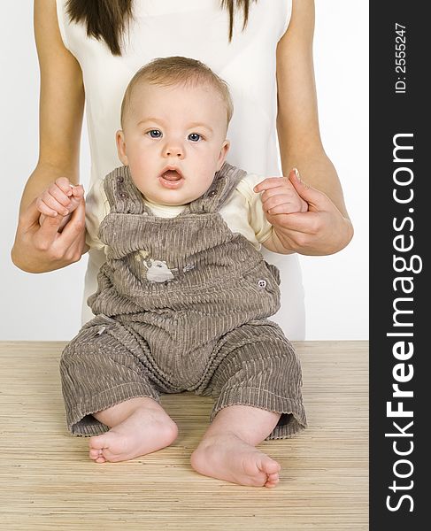 Young mother with baby boy. Baby is sitting on table. Looking at camera. Front view. Young mother with baby boy. Baby is sitting on table. Looking at camera. Front view