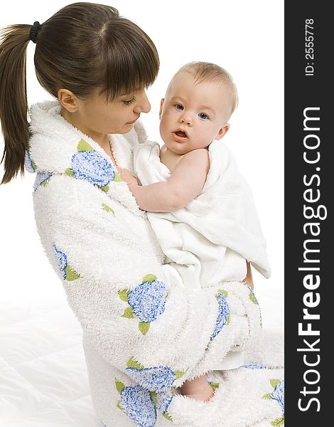 Young mother in bathrobe holding baby boy in towel. White background. Side view. Young mother in bathrobe holding baby boy in towel. White background. Side view