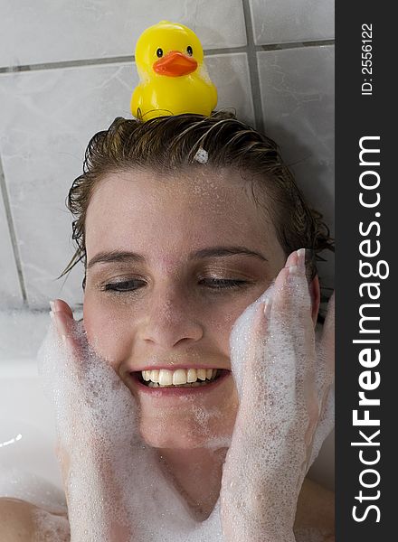 Attractive blond woman washing her face with bubbles with duck on head. Attractive blond woman washing her face with bubbles with duck on head