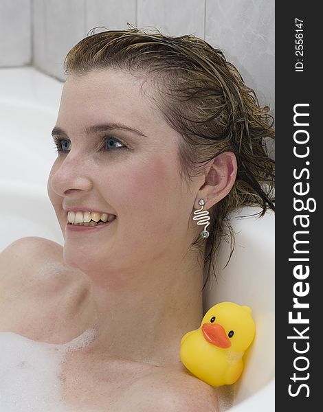 Attractive blond woman lying in bubble bath with her ducky. Attractive blond woman lying in bubble bath with her ducky