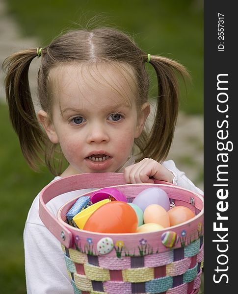 A young girl hugging a basket full of Easter eggs. A young girl hugging a basket full of Easter eggs