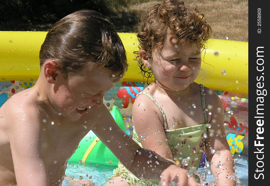 Boy in girl splashing in colorful pool. Boy in girl splashing in colorful pool.