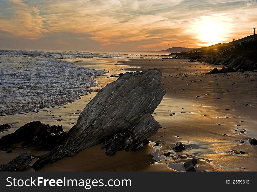 Sunset at the coast with a rock in the foreground and sea in the background. Sunset at the coast with a rock in the foreground and sea in the background