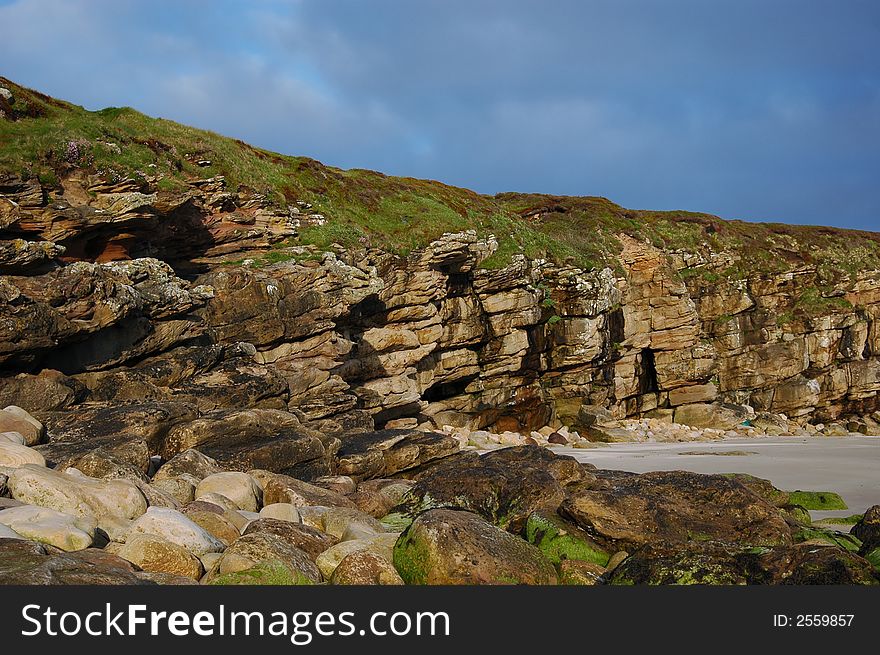 The landfall rocks and low cliffs showing erosion and geological formation of a rocky bay.