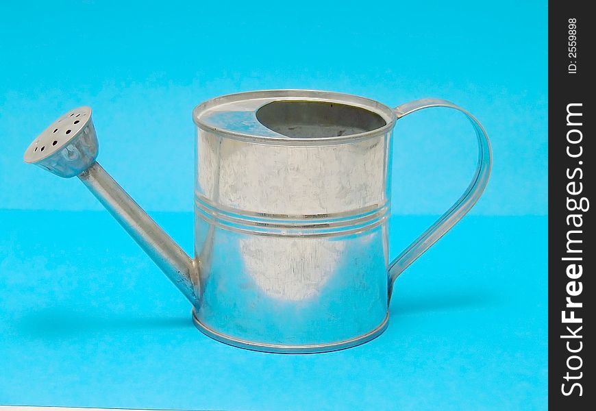 Miniature watering can isolated in blue background