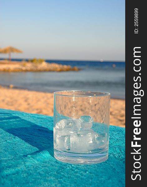 Glass with ice on a background of the sea