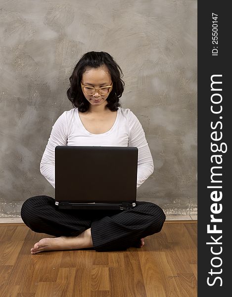 Asian woman typing with laptop notebook on the wooden floor. Asian woman typing with laptop notebook on the wooden floor