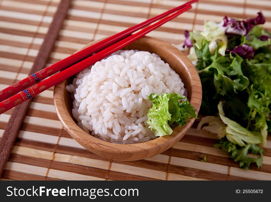 Rice in bamboo bowl with chopsticks.