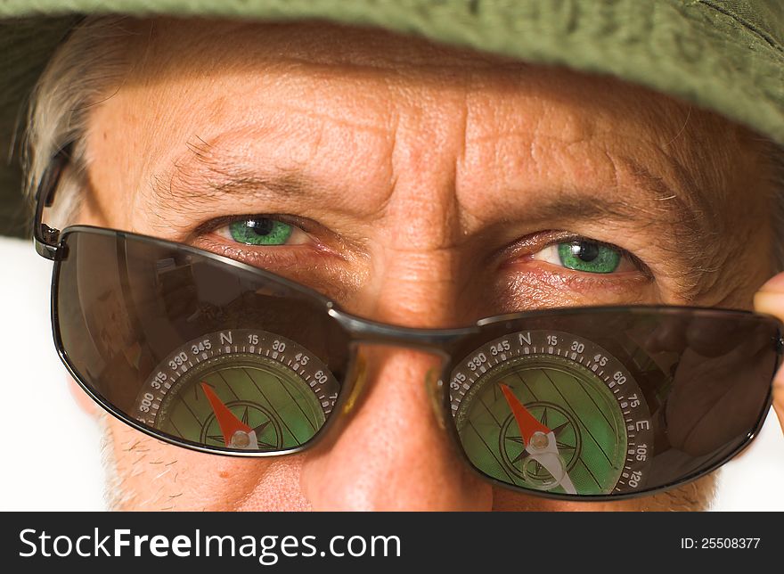 Horizontal portrait of a beardy man with a wrinkled face, wearing sun-glasses with reflexion of a compass in them. Horizontal portrait of a beardy man with a wrinkled face, wearing sun-glasses with reflexion of a compass in them.