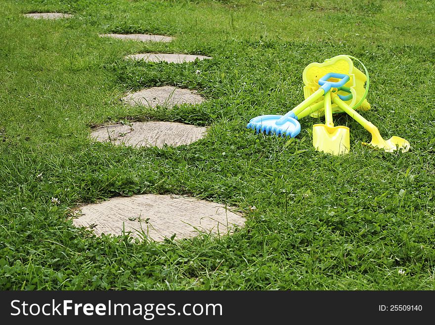 Kids Gardening Kit next to walkway of a Backyard Garden. Kids Gardening Kit next to walkway of a Backyard Garden