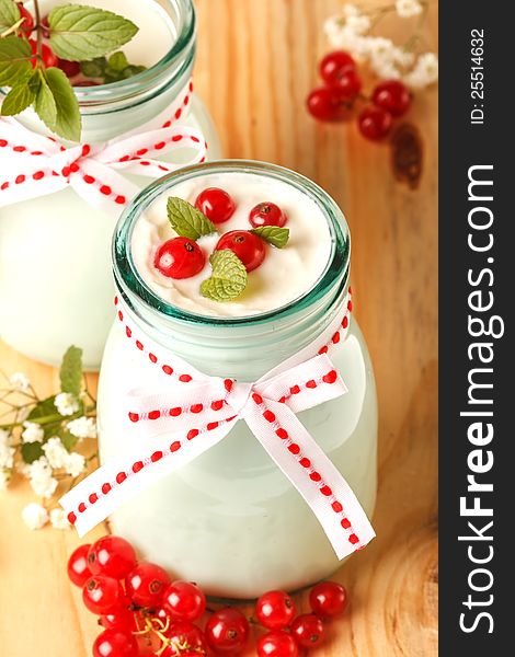 Redcurrant yoghurt with peppermint on wooden background