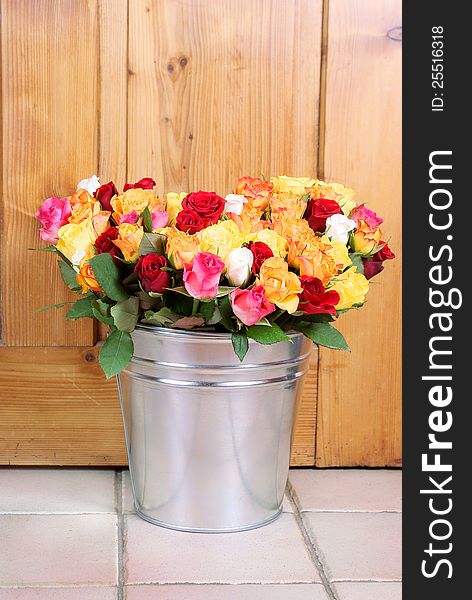 Bunch of roses in tinny bucket on a wooden background. Bunch of roses in tinny bucket on a wooden background