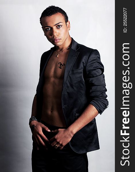 Handsome young black man with tattoo in fashion jacket posing in studio. Handsome young black man with tattoo in fashion jacket posing in studio