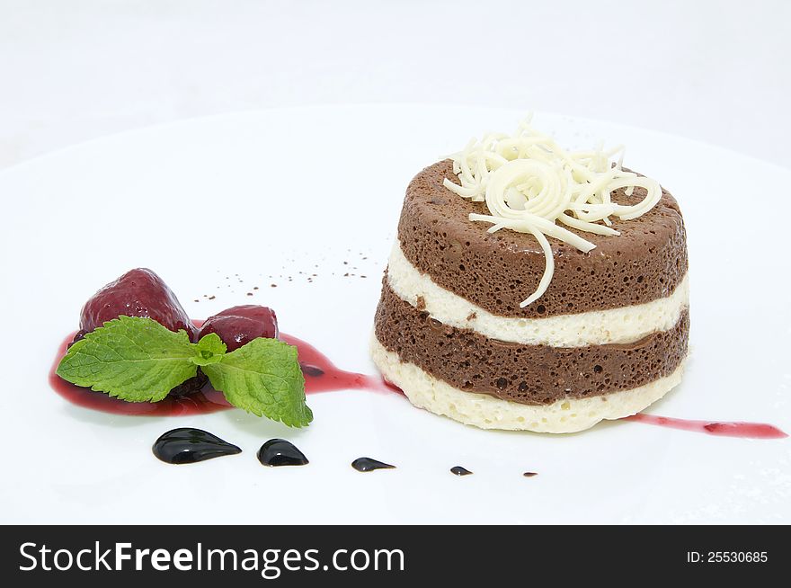 A piece of cream cake decorated with chocolate and mint. A piece of cream cake decorated with chocolate and mint