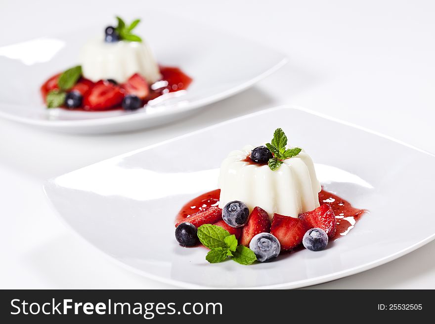 Close up photograph of a panna cotta dessert with strawberries and blueberries. Close up photograph of a panna cotta dessert with strawberries and blueberries
