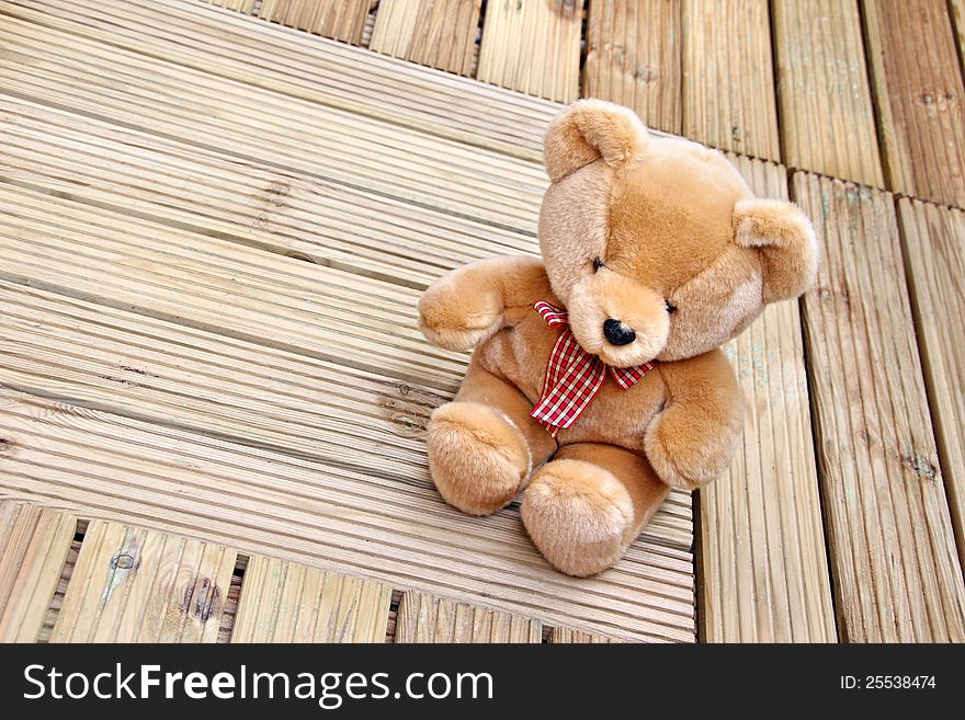 Photo of soft brown teddy bear sitting on newly laid decking. Photo of soft brown teddy bear sitting on newly laid decking.